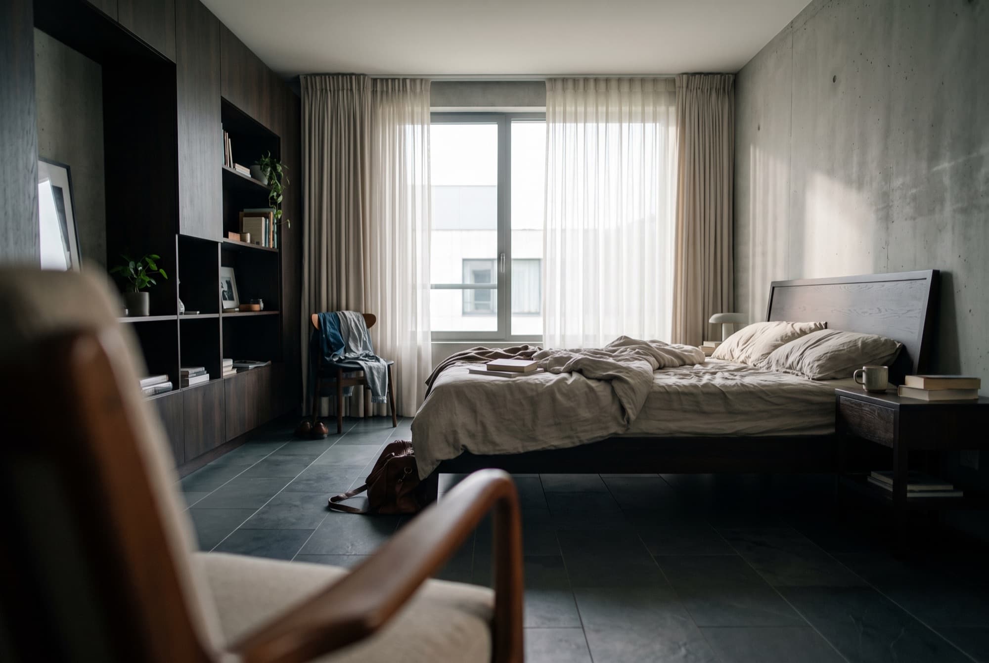 Furnished bedroom with a full-height window, sheer curtains and built-in shelving (representative image)