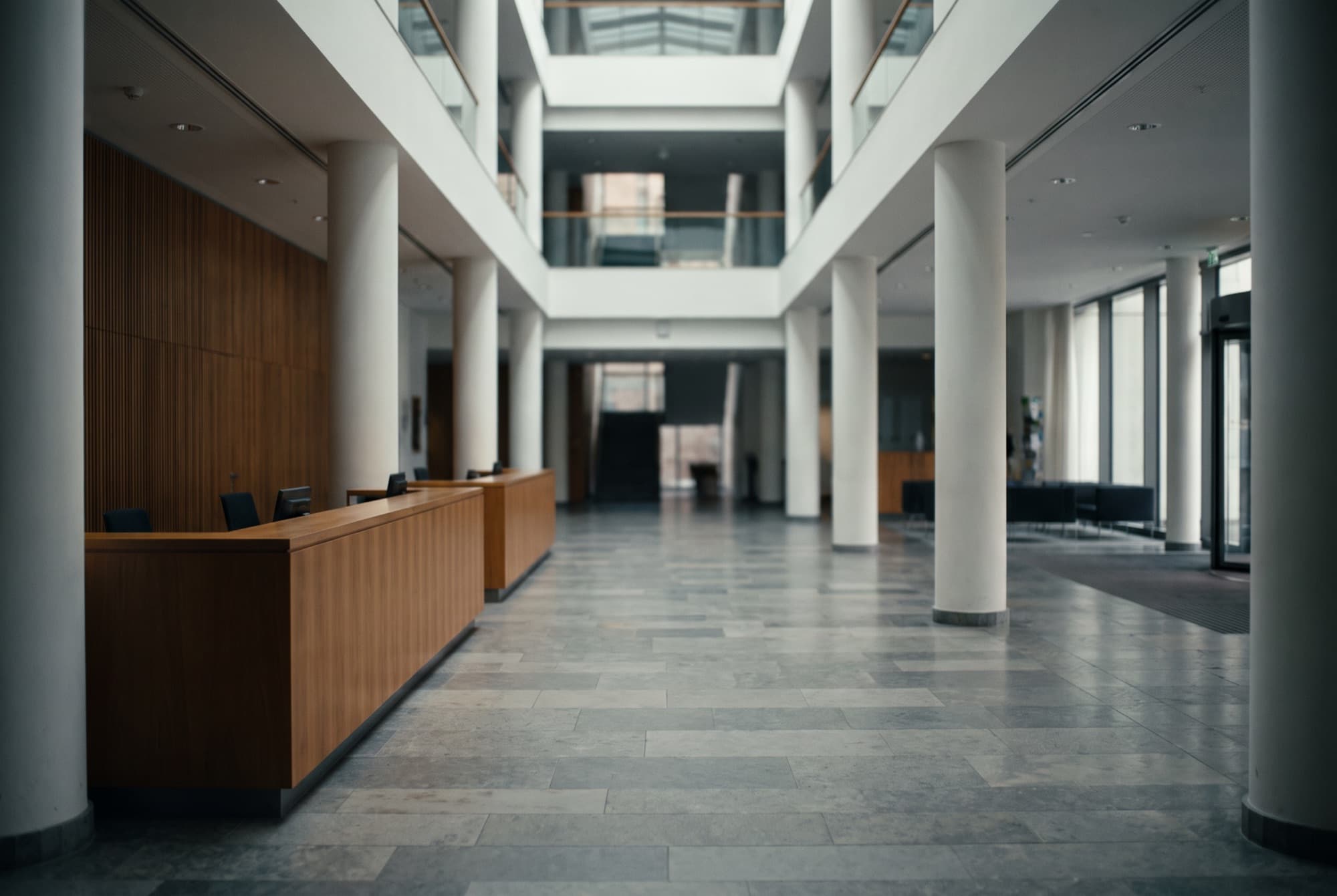 Double-height building lobby with a reception counter and full-height glazing (representative image)