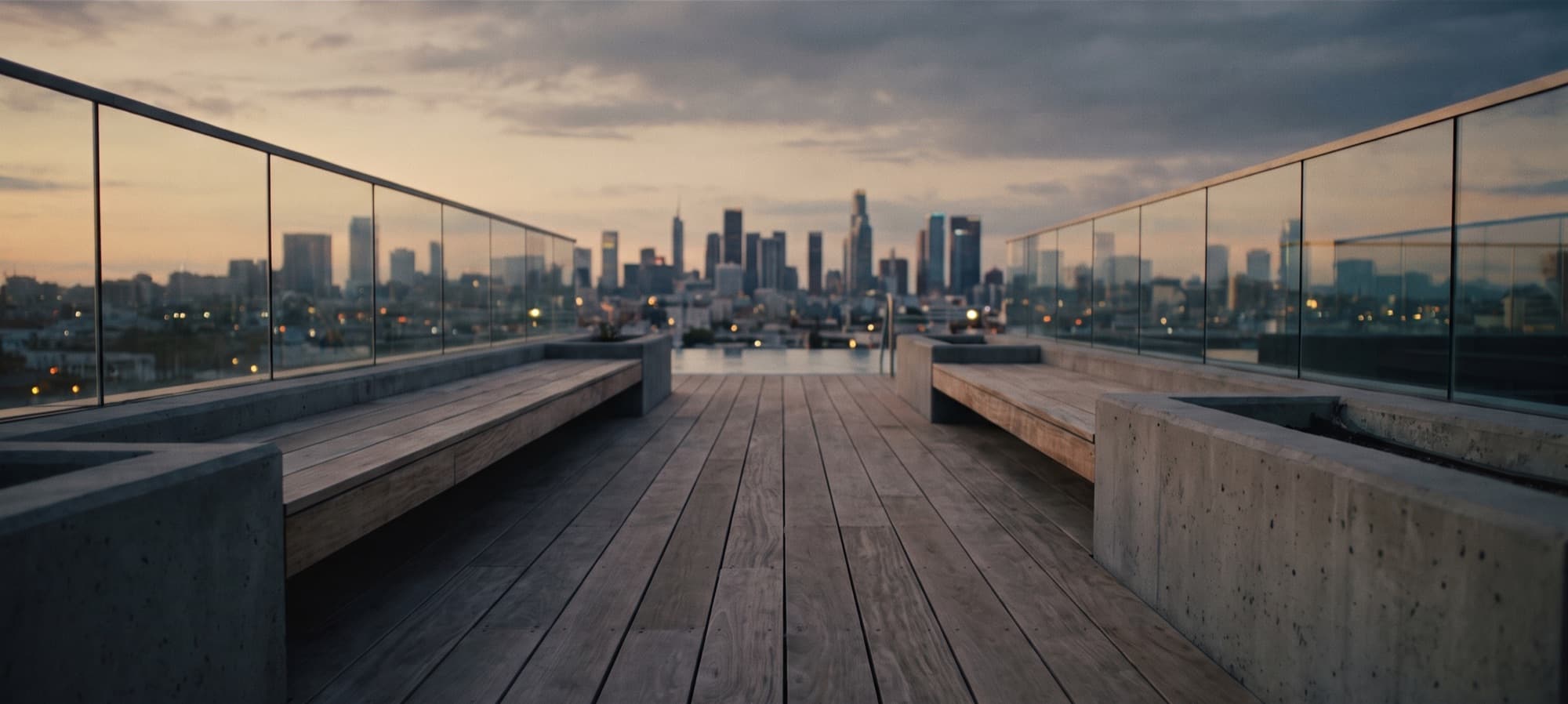 Rooftop deck with bench seating and a glass balustrade, overlooking a city skyline at dusk (representative image)